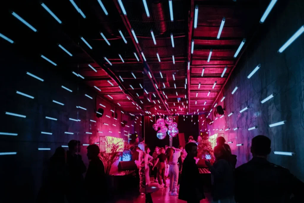 Photo by Aleksandr Popov on Unsplash -- https://unsplash.com/photos/a-group-of-people-standing-around-in-a-room-9vDdkxSCAD4
