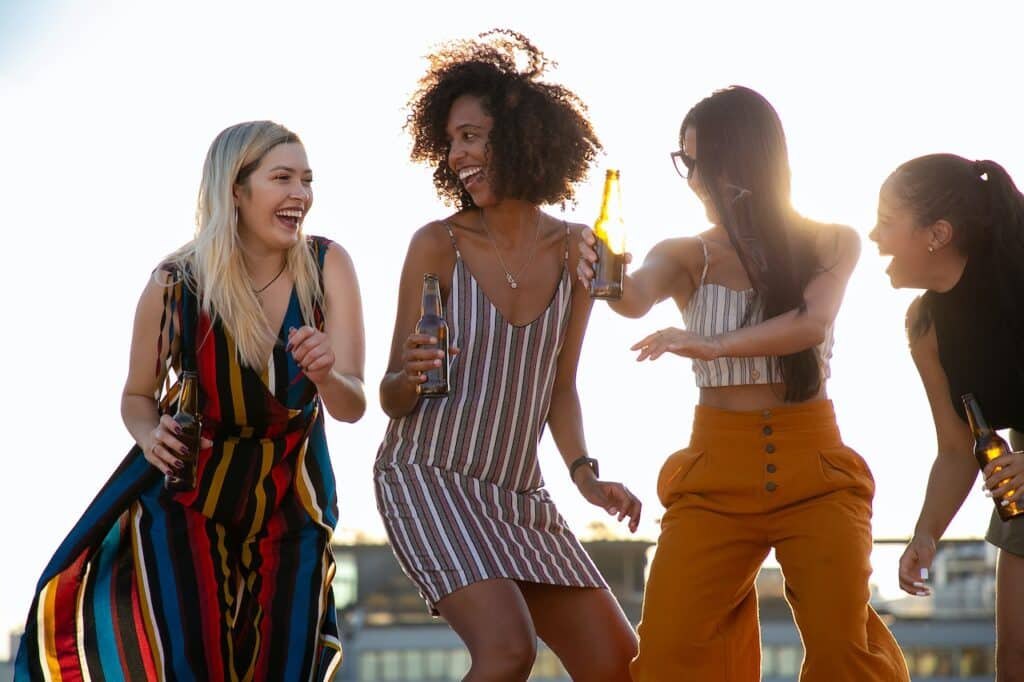 Photo by Kampus Production: https://www.pexels.com/photo/laughing-young-diverse-girlfriends-dancing-and-drinking-beer-during-event-5935240/ - outdoor event