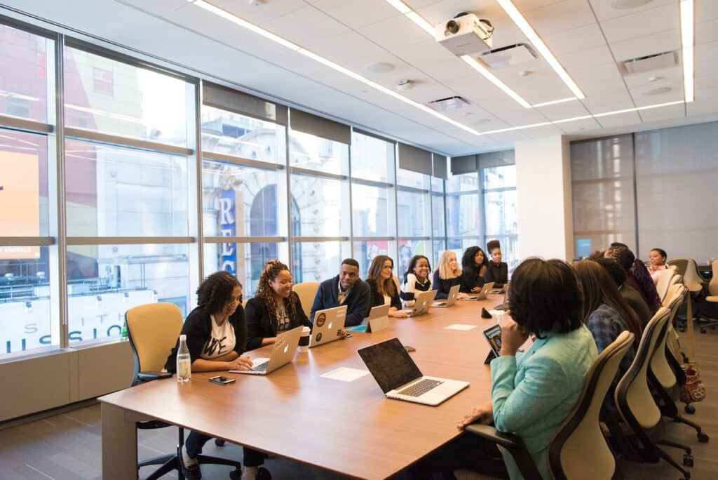 Photo by Christina Morillo: https://www.pexels.com/photo/group-of-people-on-a-conference-room-1181406/ Image Text: Hosting a Meeting Alt Text: Corporate meeting Description: Corporate meeting planning