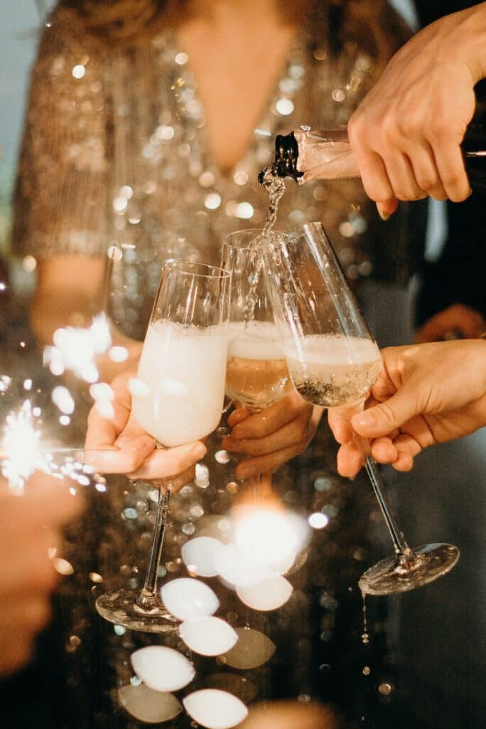 Holiday Party in NYC Photo by cottonbro studio: https://www.pexels.com/photo/person-pouring-champagne-on-champagne-flutes-3171770/