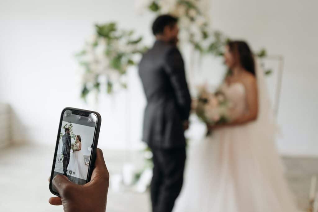 https://www.pexels.com/photo/taking-photo-of-married-couple-8815289/ Image Title: Custom Event for Wedding Image Description: Making a video of the bride and the groom Alt Text: Blending Pixels with Emotions