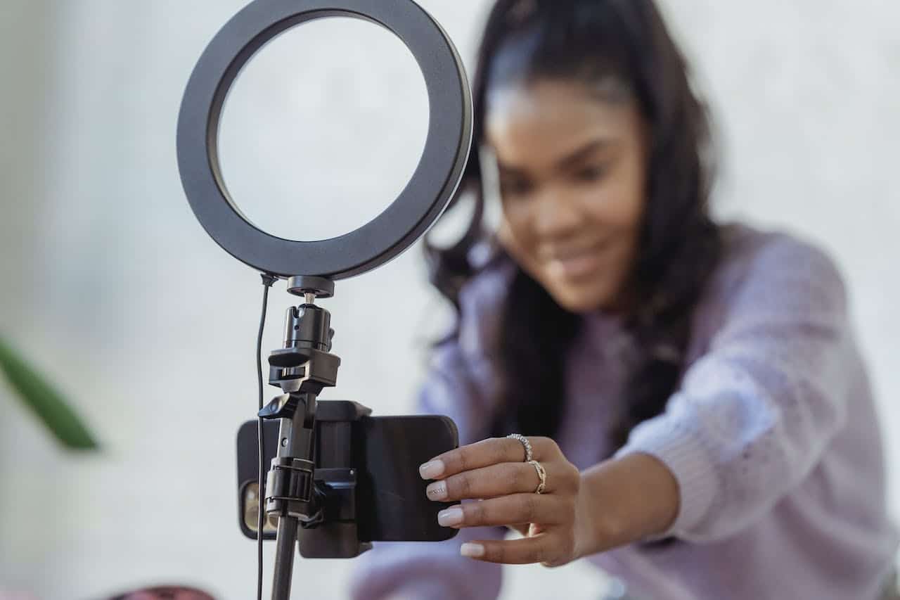 Image Title: Influencer Marketing in Action Image Description: Content creator prepares to record a promotional video Alt Text: Video Marketing Setup Source: https://www.pexels.com/photo/happy-young-black-woman-setting-up-smartphone-before-shooting-podcast-6954220/