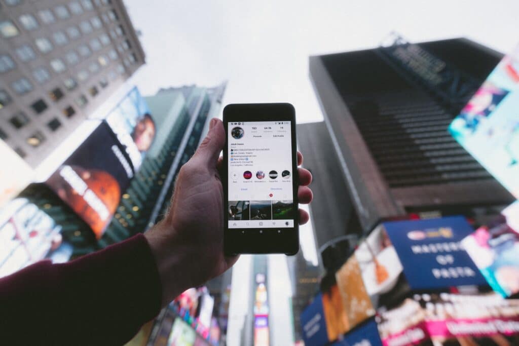 Source: https://unsplash.com/photos/high-angle-photo-of-person-holding-turned-on-smartphone-with-tall-buildings-background-WUmb_eBrpjs Title: Social Media Marketing Alt. Title: Social Media Event Promotion Description: A person using Instagram on their phone
