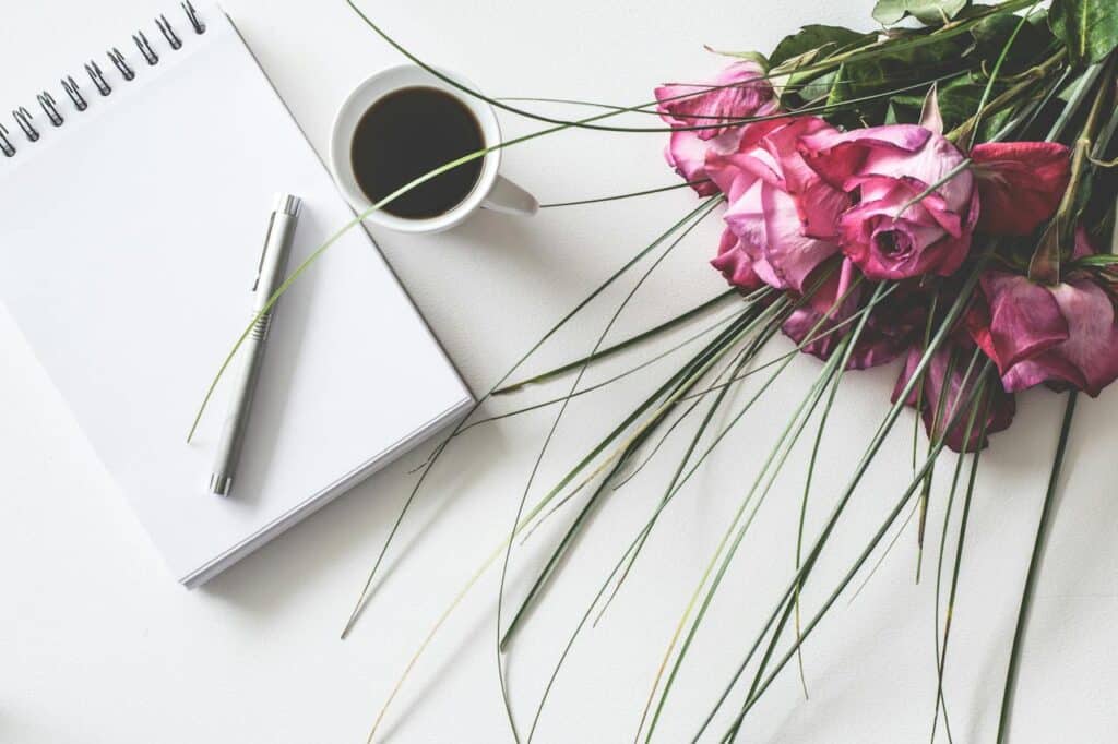 Photo by Lum3n from Pexels: https://www.pexels.com/photo/red-rose-flowers-bouquet-on-white-surface-beside-spring-book-with-click-pen-and-cup-of-cofffee-1410226/