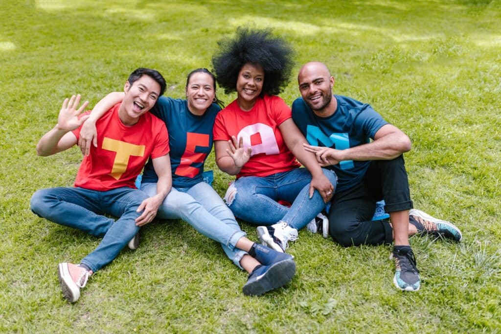 Photo by RDNE Stock project: https://www.pexels.com/photo/people-sitting-on-grass-with-happy-faces-7551425/ -- team building events