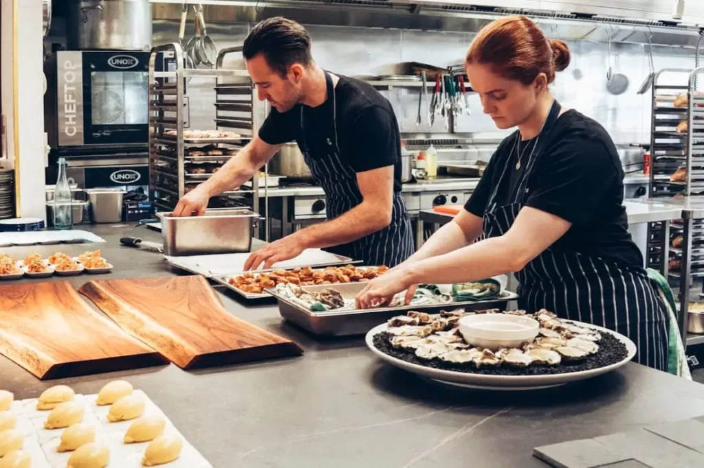 Photo by Elle Hughes: https://www.pexels.com/photo/man-and-woman-wearing-black-and-white-striped-aprons-cooking-2696064/ -- catering and event food service