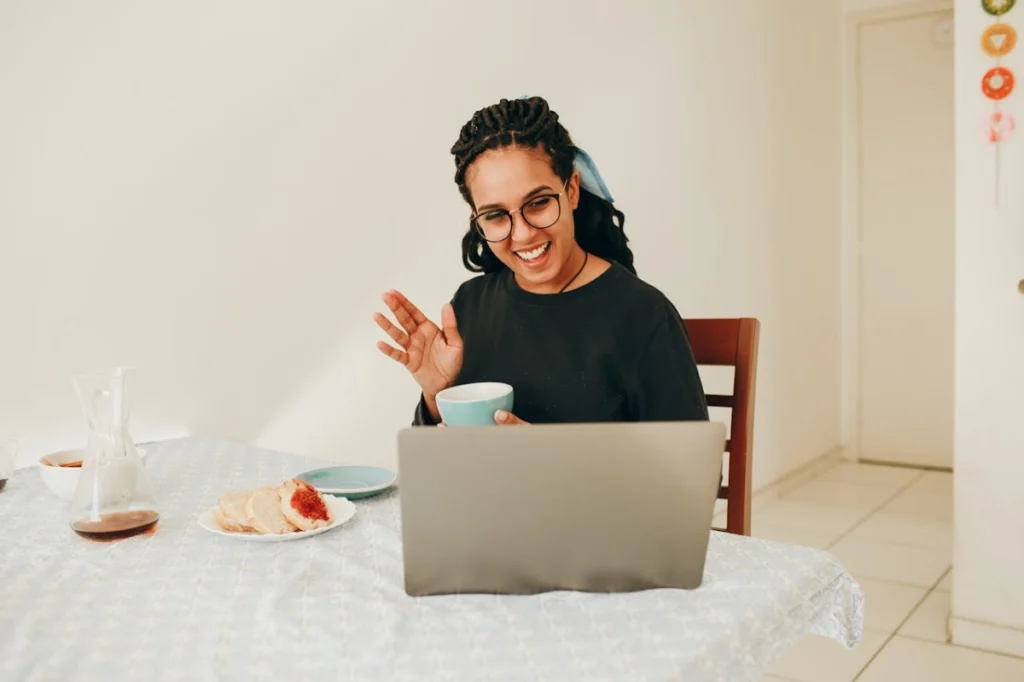 Photo by Helena Lopes: https://www.pexels.com/photo/woman-holding-cup-talking-online-via-laptop-27176547/ -- remote employee, virtual corporate event
