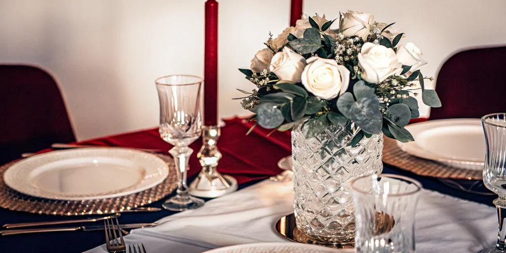 Elegant event table setting with white roses and red candles.