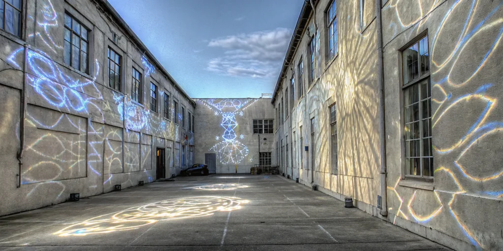Colorful projection mapping transforms a building facade with geometric light patterns.