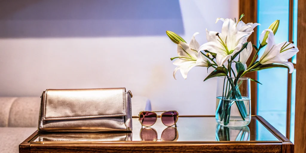 A modern brand showcase of stylish products including a clutch, sunglasses, and flowers.