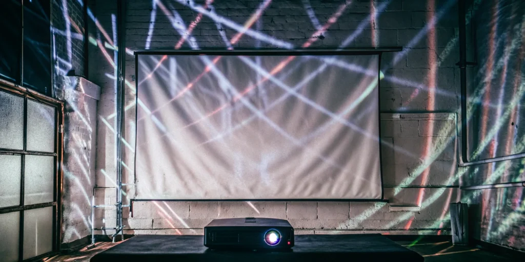 A projector casts colorful lights for a projection mapping display at an event.