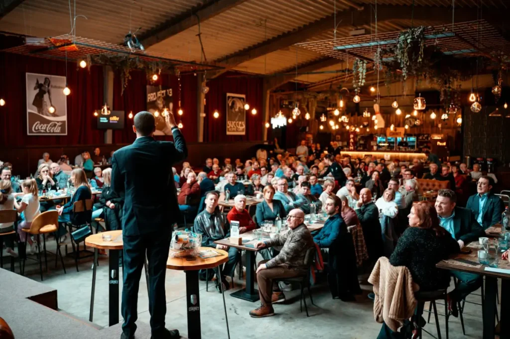 Photo by Jitte Davidson: https://www.pexels.com/photo/speaker-engaging-audience-in-packed-venue-35755223/