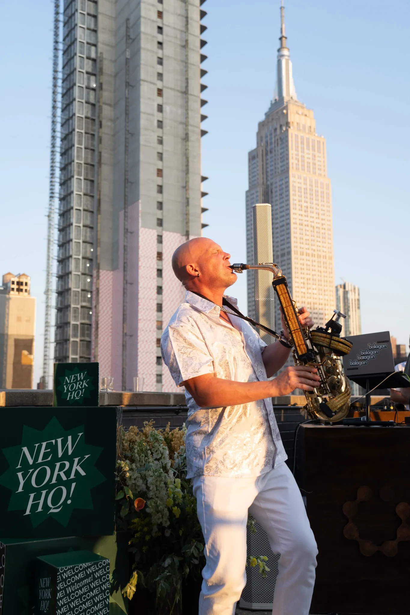 Saxophonist performing on a NYC rooftop with the Empire State Building in view, EMRG Media