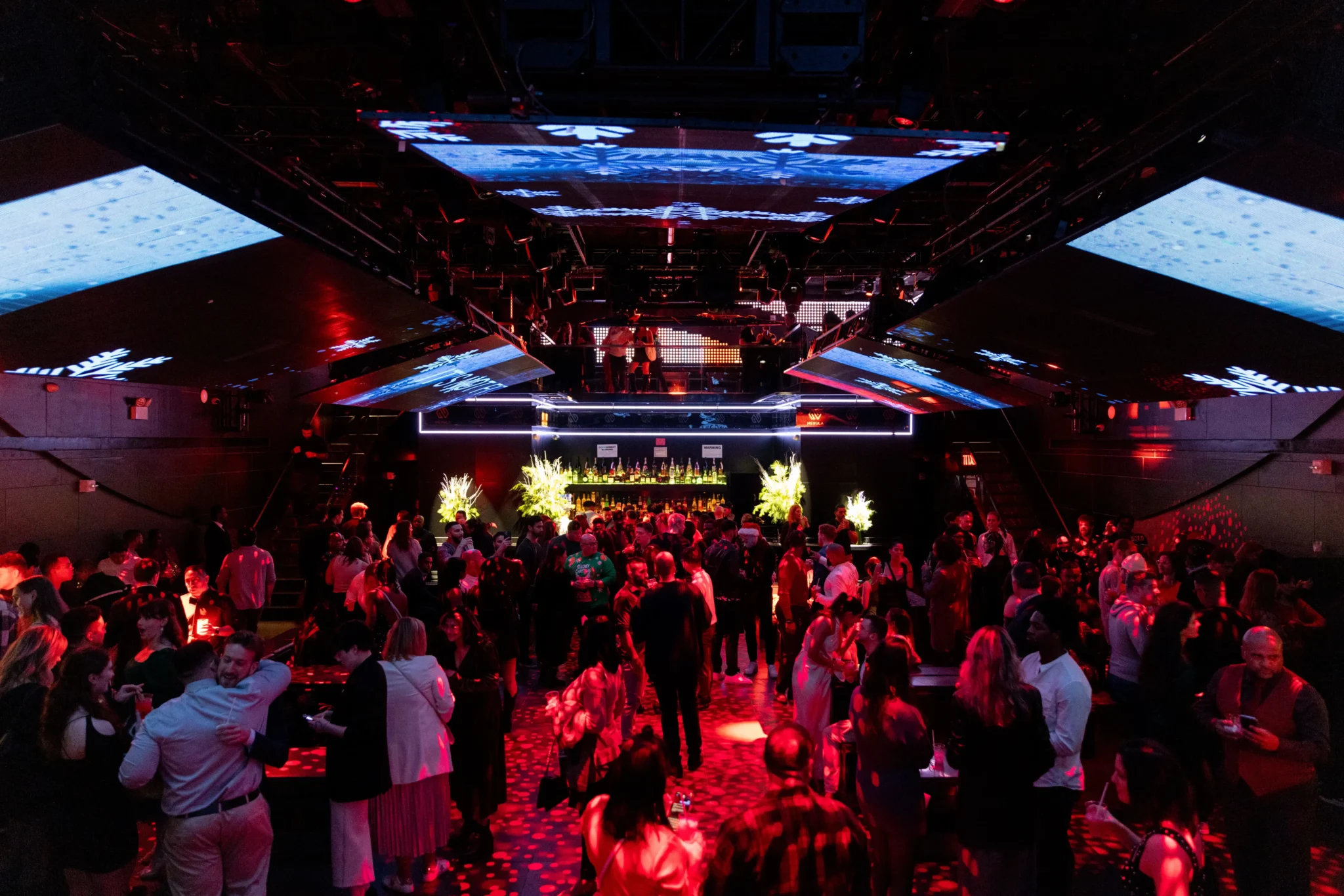 Crowd gathered under LED snowflake screens at a red-lit NYC event venue, EMRG Media