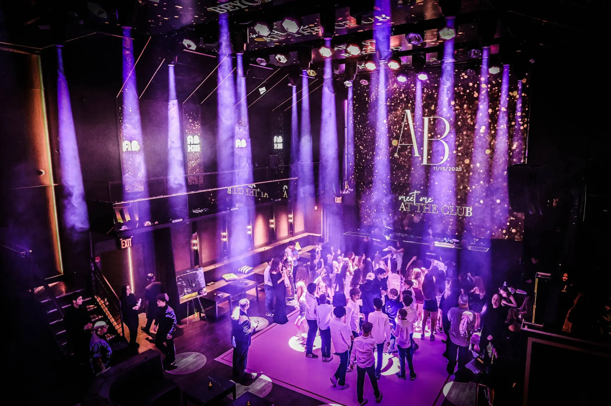 Guests dancing under purple beam lighting at an "AB, Meet Me at the Club" themed NYC private event, EMRG Media