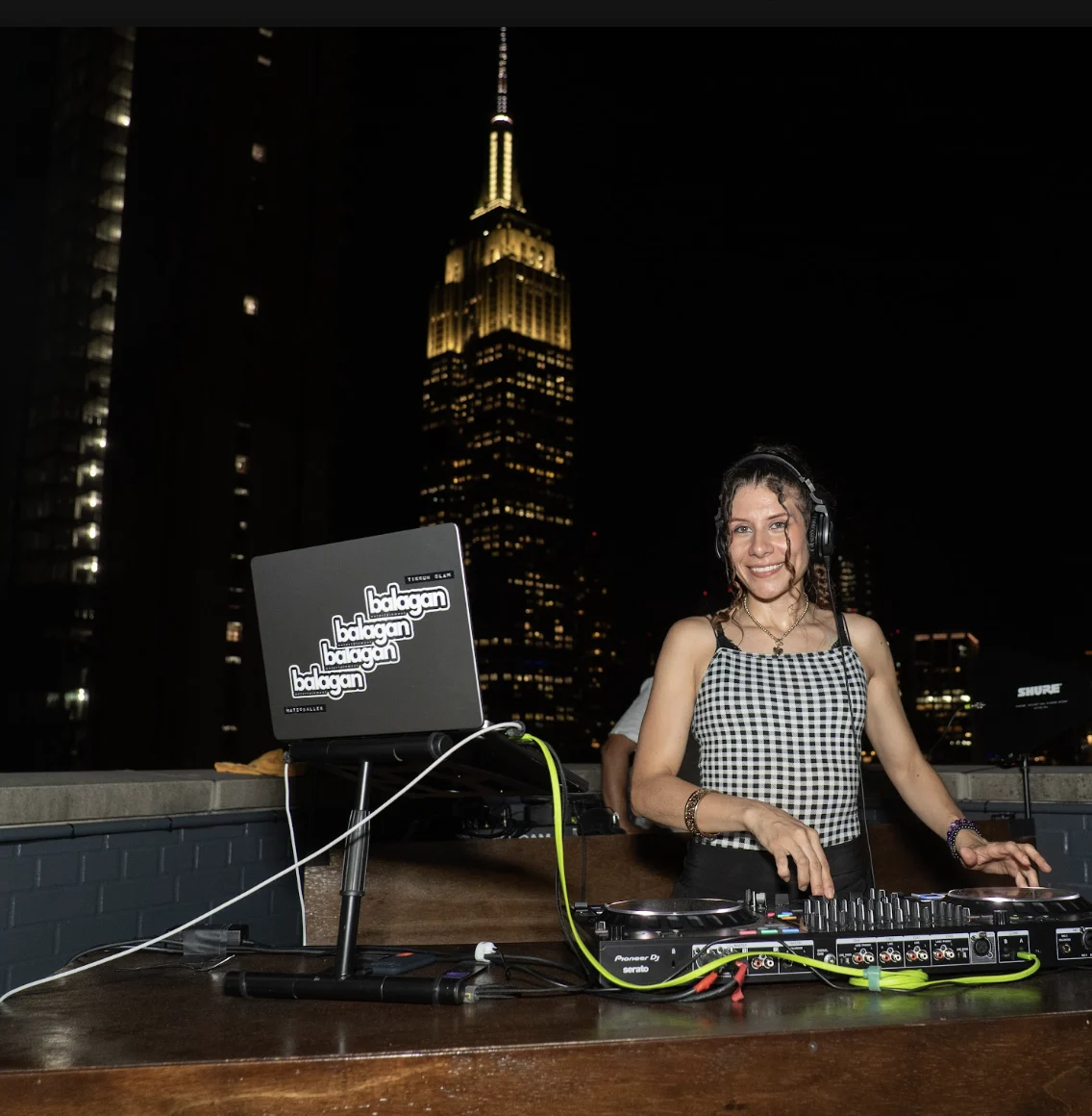 DJ spinning on a NYC rooftop with the Empire State Building in the background, EMRG Media
