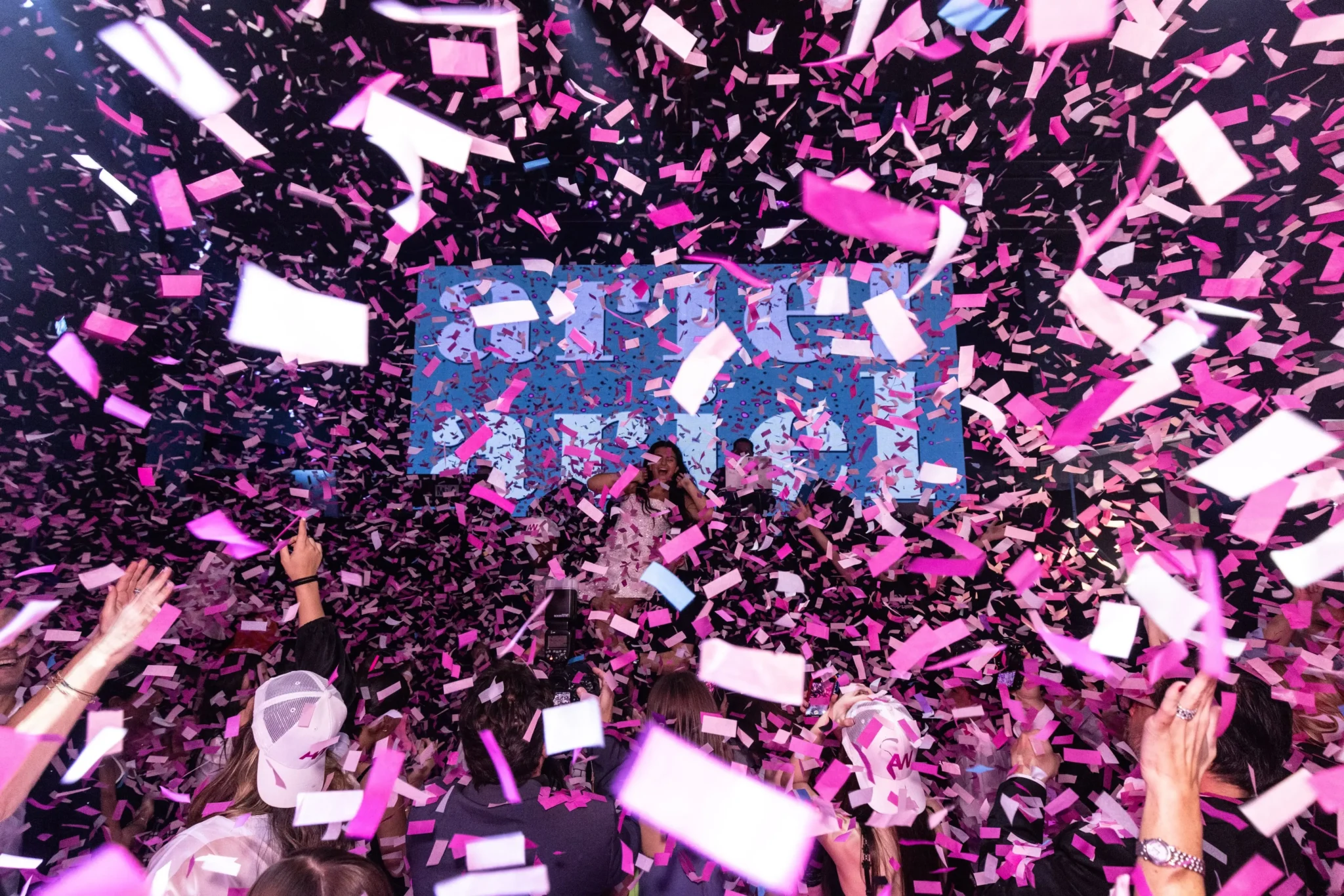 Pink and white confetti burst over a performer on stage at a NYC branded event, photographed by EMRG Media